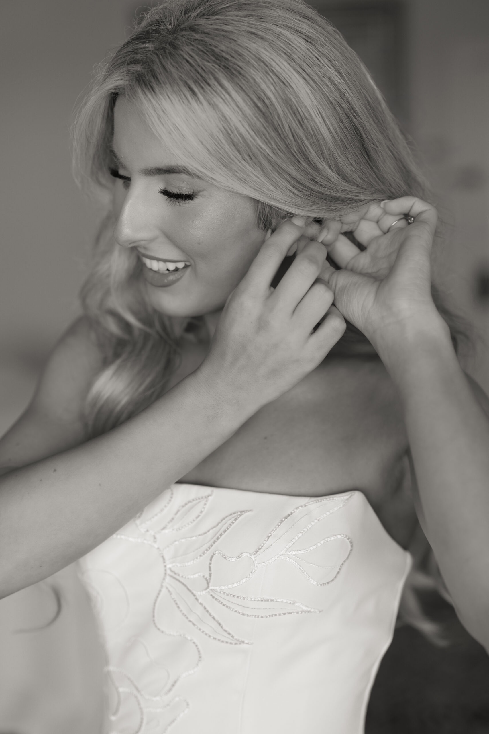 Black and white close-up of a bride putting on earrings while getting ready for her wedding day in Tampa Bay, Florida