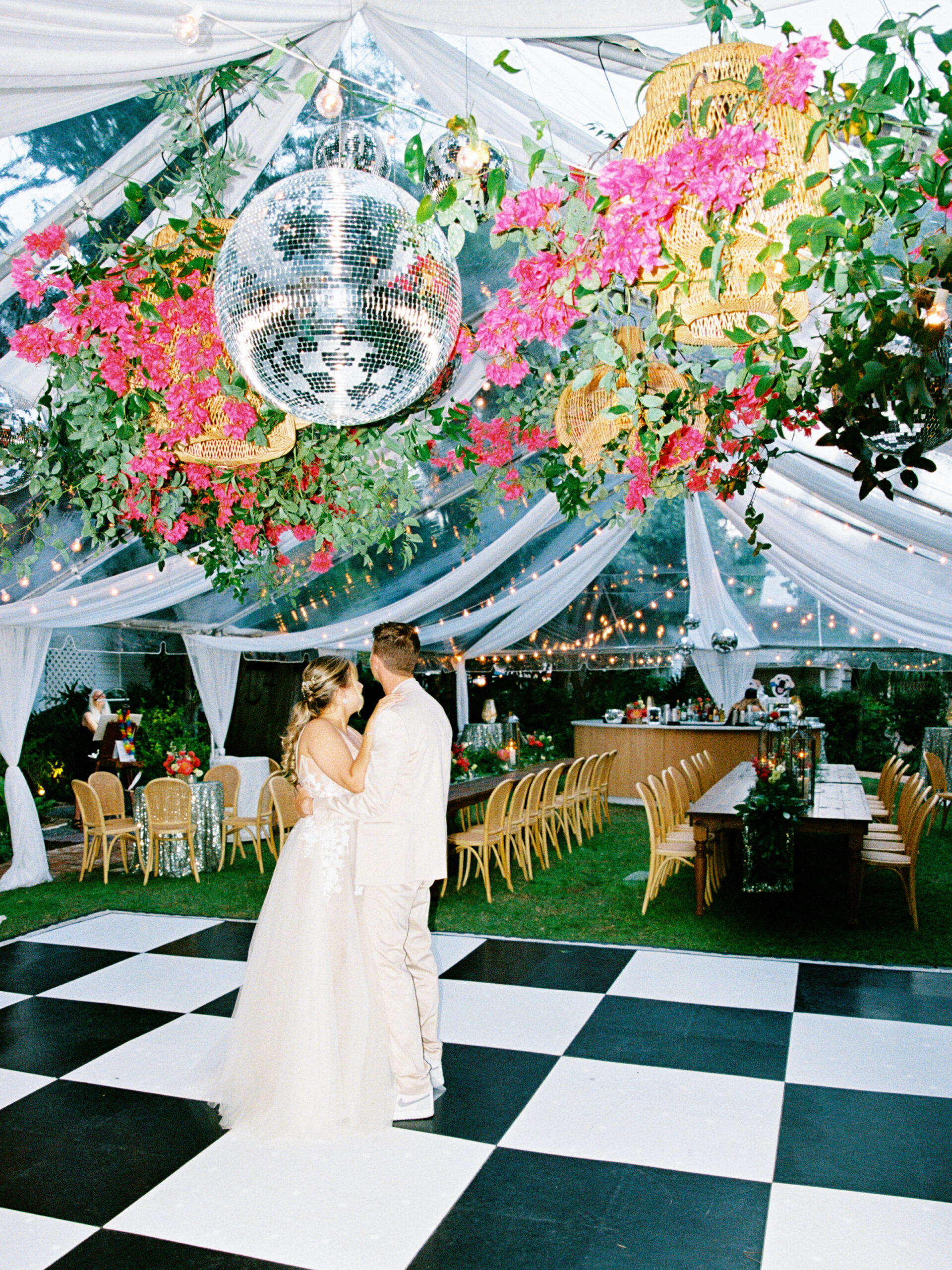 Bride and groom sharing a quiet moment on the dance floor beneath floral installations and disco balls during a destination wedding reception in Key West
